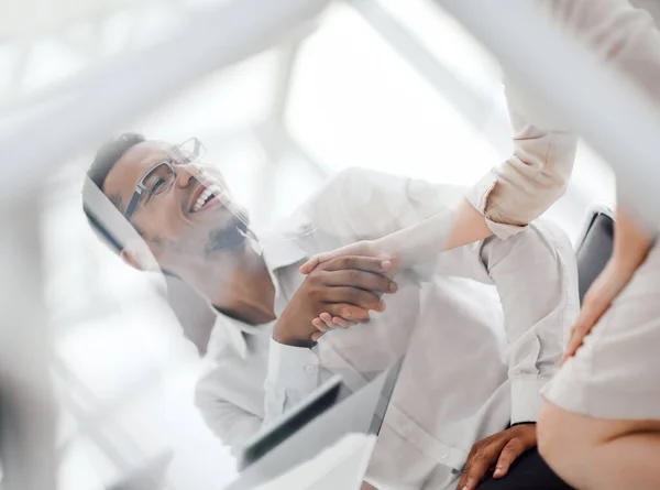 Bottom view.handshake employees at the Desk in the office . — Stock Photo, Image