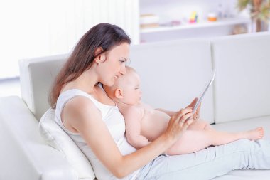 Anne ve bebek oynamak ve tablet bilgisayar okumak için arıyorsunuz