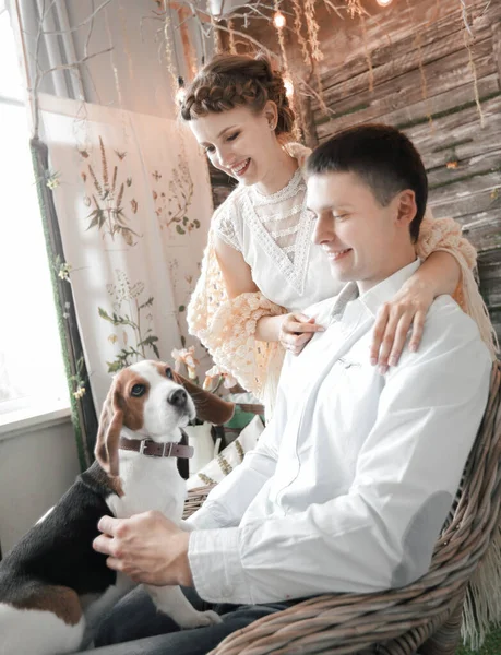 Pareja joven con mascota sentada en una silla — Foto de Stock