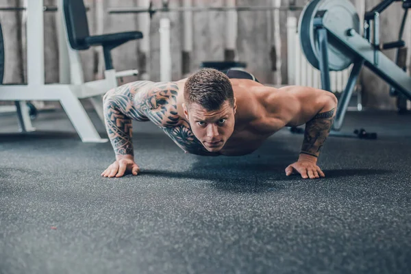 Bodybuilder κάνει push-ups στο γυμναστήριο. φωτογραφία με χώρο αντιγραφής — Φωτογραφία Αρχείου