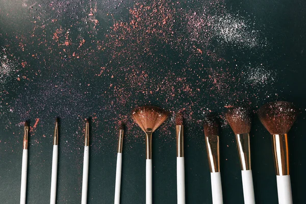 nine professional makeup brushes on a black background