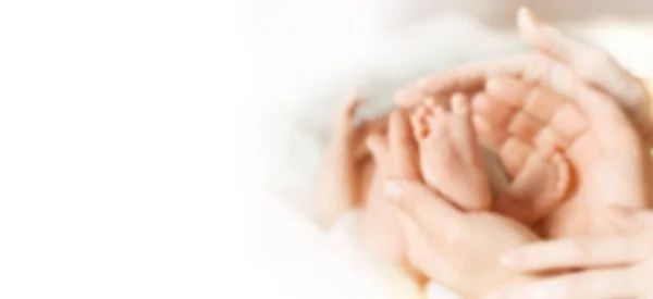 Blurred image for the advertising text. photo with copy space. legs newborn baby in the hands of his parents — Stock Photo, Image