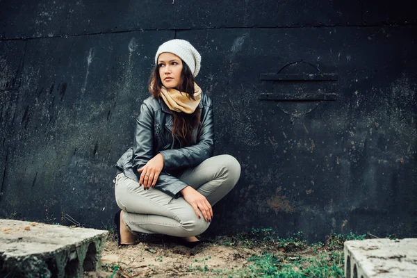 sad young woman sitting near black wall
