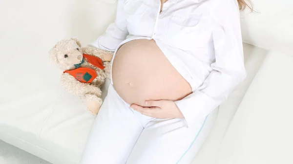 Primo piano.bella donna incinta con un peluche sdraiato sul divano . — Foto Stock