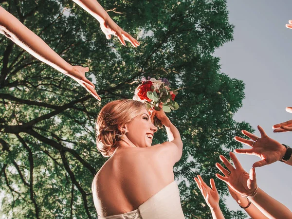 Веселая невеста бросает свадебный букет своим друзьям . — стоковое фото