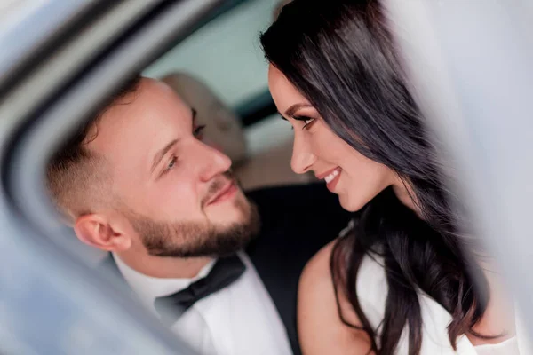Doe dicht. de bruid en bruidegom kijken elkaar zittend in de auto aan — Stockfoto