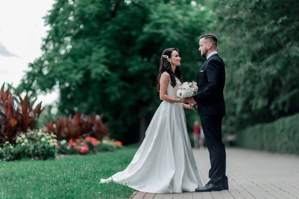 Невеста и жених стоят на тропинке в городском парке — стоковое фото
