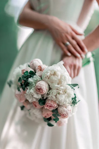 Vicino. la sposa tiene il bouquet da sposa alle sue spalle . — Foto Stock