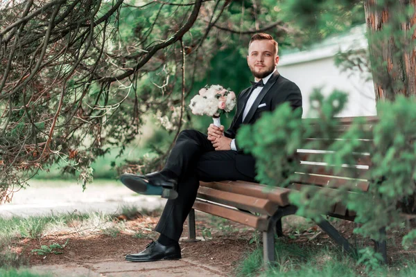 Groom is waiting for the bride sitting sitting on the bench. — Stock Photo, Image