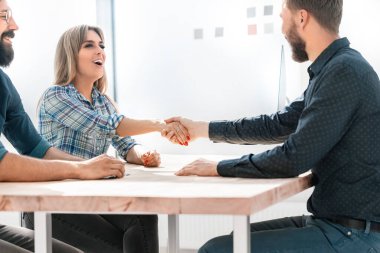 Gülümseyen iş kadını iş ortağıyla tokalaşıyor.