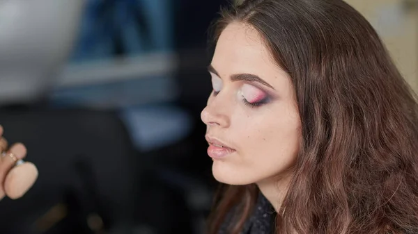 Artista de maquiagem profissional faz maquiagem para uma jovem mulher — Fotografia de Stock
