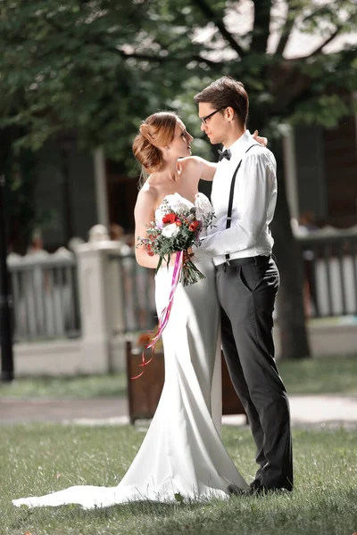 Hermosa pareja amorosa de pie en el césped en el parque de la ciudad — Foto de Stock