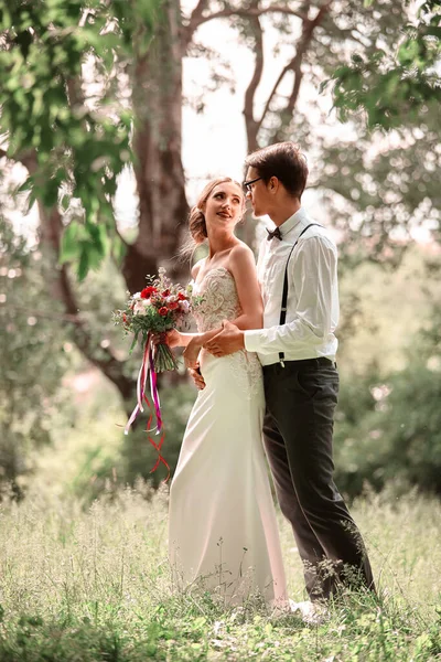 Recém-casados caminham na natureza no dia do casamento . — Fotografia de Stock