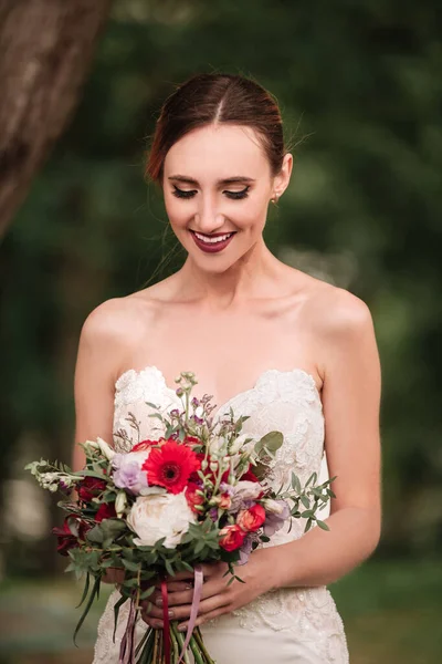 Hermosa novia en un vestido de novia y un ramo de bodas —  Fotos de Stock