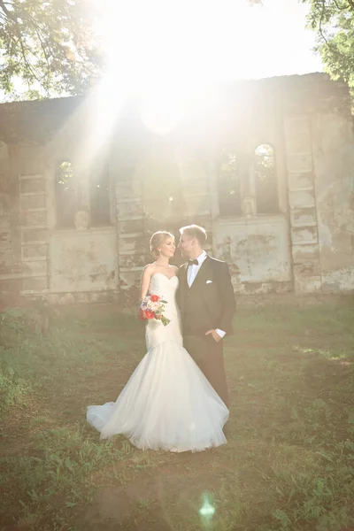 Couples of newlyweds standing near the old manor in the evening — Stock Photo, Image