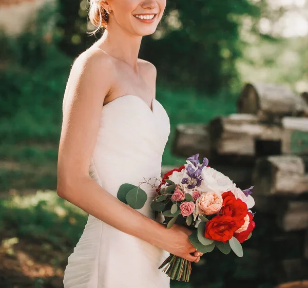 Noiva com um buquê de flores em um fundo borrado do Parque . — Fotografia de Stock