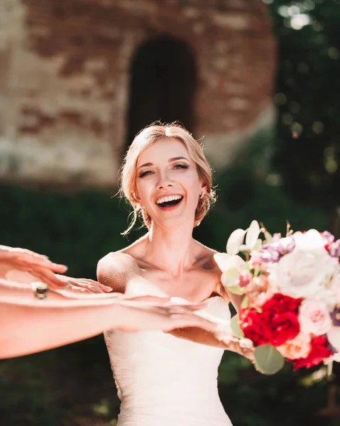 Süße Braut reicht Hochzeitsstrauß in den Händen ihrer Freunde. — Stockfoto