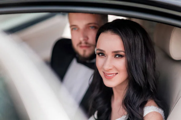 Close up. a happy couple of newlyweds sitting in the car. — Stock Photo, Image