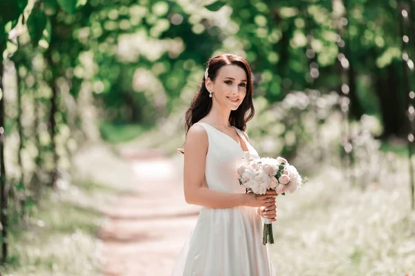 Porträt einer glücklichen Braut, die unter einem Bogen im Park steht — Stockfoto