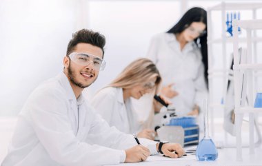 Kapat. Laboratuvardaki masasında oturan genç bilim adamı.