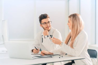 Doktor meslektaşlar ofiste masada otururken konuşuyor.