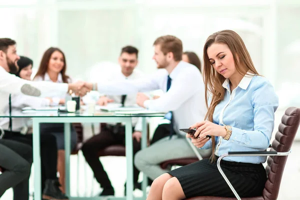 Junger Mitarbeiter mit Smartphone im Hintergrund des Business-Teams — Stockfoto