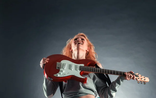 Menina atraente emocionalmente tocando a guitarra elétrica . — Fotografia de Stock