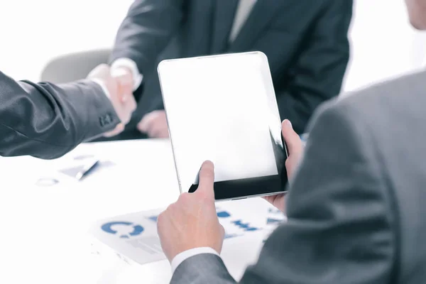 Businessman with a digital tablet on the background of a handshake of business partners — Stock Photo, Image