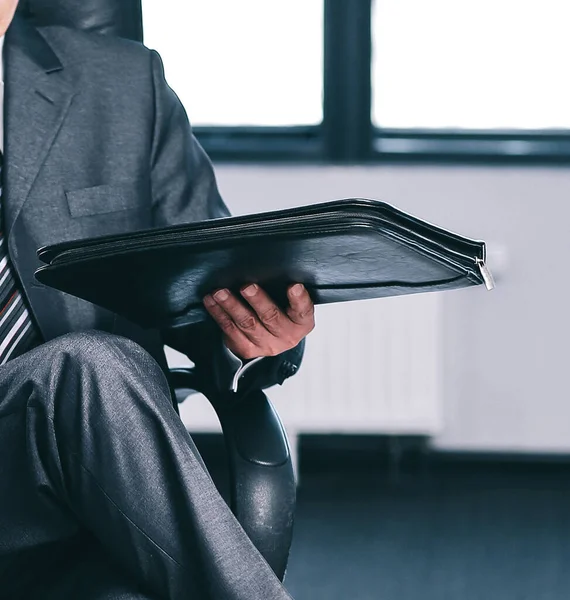 Selbstbewusster Geschäftsmann mit Ledermappe, der im Büro sitzt — Stockfoto