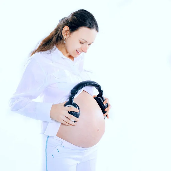 Szczęśliwy w ciąży kobieta stawia słuchawki na brzuszku — Zdjęcie stockowe