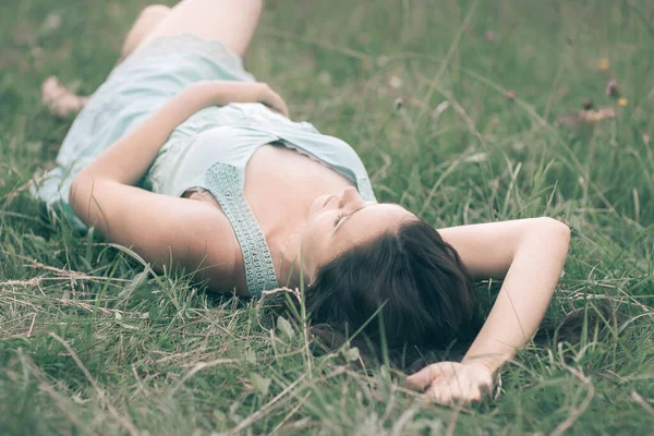 Niedliche junge Frau liegt an einem Sommertag im Gras — Stockfoto