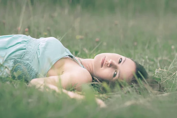 Atraktivní mladá žena sní o ležení na trávě — Stock fotografie