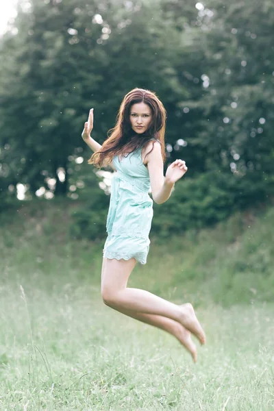 Mujer joven disfrutando de saltar sobre hierba fresca — Foto de Stock