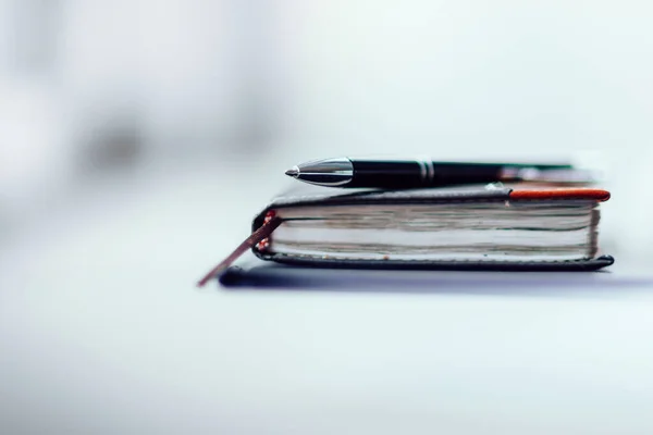 Блокнот и ручка на фоне рабочего стола — стоковое фото