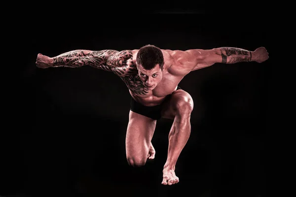 Μυώδης άνθρωπος bodybuilder δείχνει τους μυς του, ενώ στέκεται στο γόνατό του. — Φωτογραφία Αρχείου