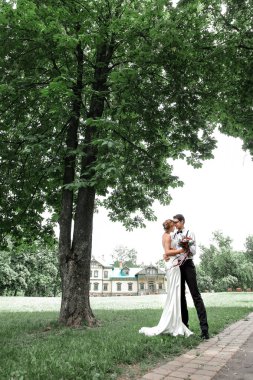 Mutlu yeni evliler evlerinin yakınındaki çimlerin üzerinde duruyorlar..