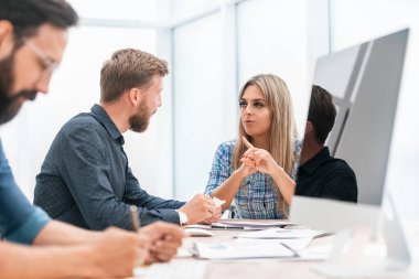 Kapat. Ofis masasında oturan iş arkadaşları konuşuyor..
