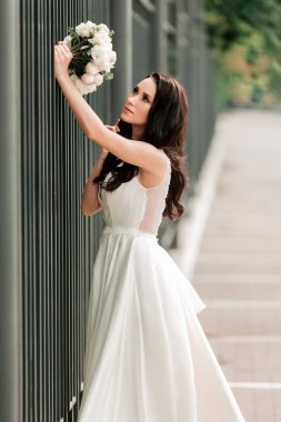 Bir şehir sokağında düğün buketi olan mutlu gelin.