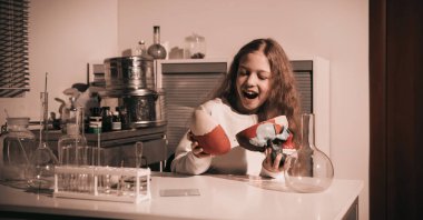 Laboratuarındaki masada oturan mutlu liseli kız.