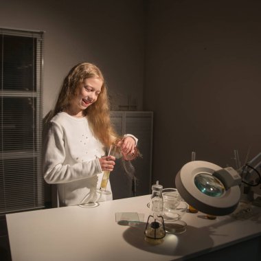 Gülümseyen kız öğrenci araştırma kimya bürosu yönetiyor.