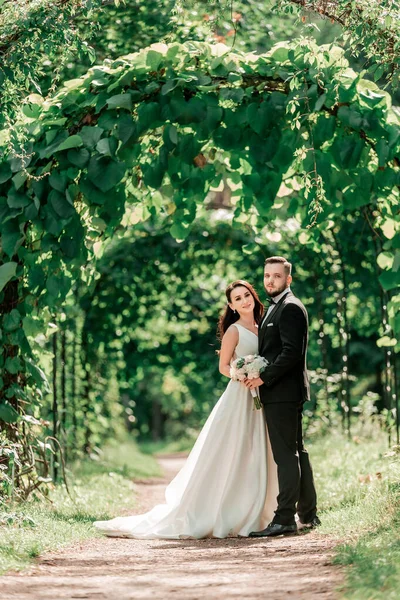 Noiva feliz e noivo de pé sob o arco de casamento — Fotografia de Stock