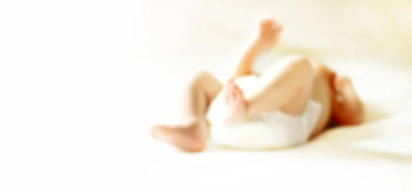 Imagen de las piernas del bebé acostado en la cama. imagen borrosa para el texto publicitario . — Foto de Stock