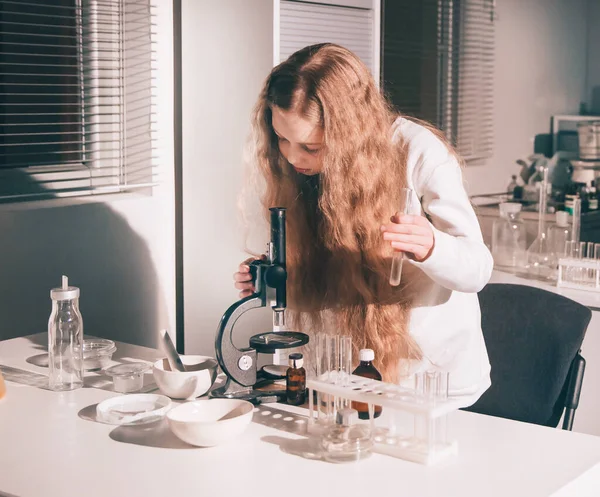 Дівчина школярка використовує мікроскоп в шкільній лабораторії . — стокове фото