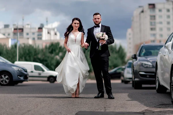Glad brud och brudgum promenader ner på gatan i storstaden — Stockfoto