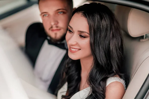 De cerca. una feliz pareja de recién casados sentados en el coche . —  Fotos de Stock