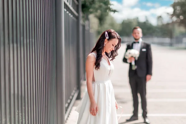 Happy bride in wedding dress standing on city street — Stock Photo, Image