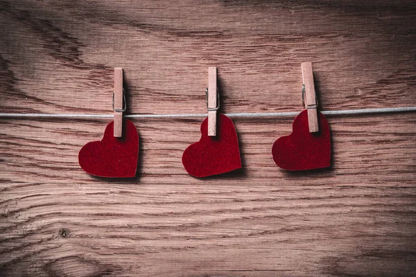 Röda hjärtan på klädnypor på trä bakgrund — Stockfoto