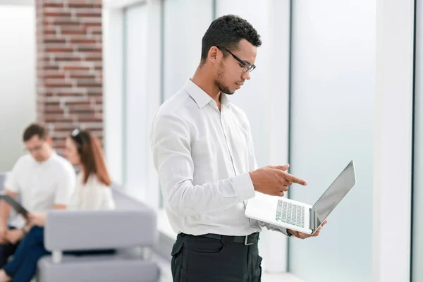 Empleado escribiendo en un ordenador portátil de pie en la oficina . — Foto de Stock