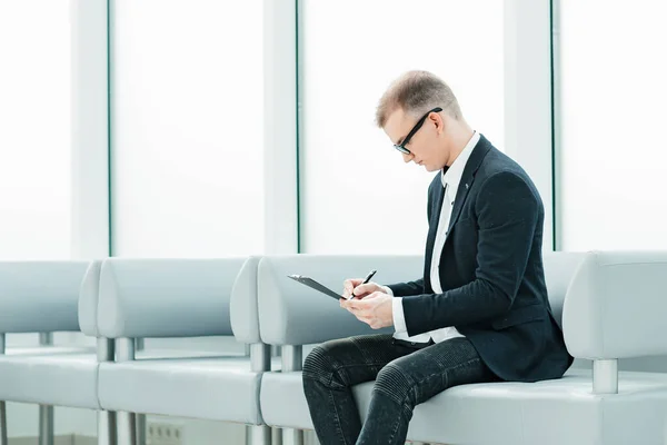 Homme d'affaires lisant un document d'affaires assis dans le hall du bureau — Photo