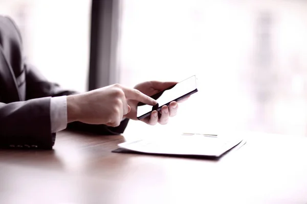 De cerca. hombre de negocios escribiendo en un teléfono inteligente, sentado en el escritorio — Foto de Stock